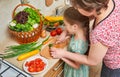 Mother and daughter with basket of vegetables and fresh fruits in kitchen interior. Parent and child. Healthy food concept Royalty Free Stock Photo