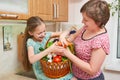 Mother and daughter with basket of vegetables and fresh fruits in kitchen interior. Parent and child. Healthy food concept Royalty Free Stock Photo