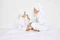 mother and daughter in bathrobes and towels apply cream Royalty Free Stock Photo