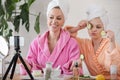 Mother and daughter in bathrobes and towels on head using natural cosmetics and having fun together at home Royalty Free Stock Photo