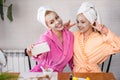 Mother and daughter in bathrobes and towels on head using natural cosmetics and having fun together at home Royalty Free Stock Photo