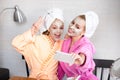 Mother and daughter in bathrobes and towels on head using natural cosmetics and having fun together at home Royalty Free Stock Photo