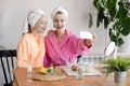 Mother and daughter in bathrobes and towels on head using natural cosmetics and having fun together at home Royalty Free Stock Photo