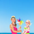 Mother and daughter on beach holding colorful windmill toy Royalty Free Stock Photo