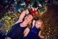 Mother and daughter in blue dresses lie under the Christmas tree Royalty Free Stock Photo