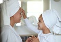 Mother and daughter bonding and spending time together on a spa day at the family home. Little girl applying face cream Royalty Free Stock Photo