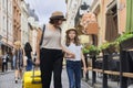 Mother and daughter child traveling tourists with suitcase on the street of an old tourist city