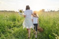 Mother and daughter child walking along the meadow, view from the back Royalty Free Stock Photo