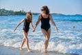 Mother and daughter child walking together on beach holding hands Royalty Free Stock Photo