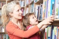 Mother And Daughter Choosing Book From Library Shelf Royalty Free Stock Photo