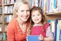Mother And Daughter Choosing Book From Library Shelf Royalty Free Stock Photo