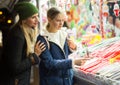 Mother with daughter choosing Christmas sweet and candy at Christmas market in evening Royalty Free Stock Photo