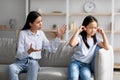 Mother daughter conflict. Young asian mom trying to speak to her offended little child, sitting together on sofa at home Royalty Free Stock Photo