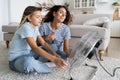 Mother and daughter cooling down while sitting on floor in front of electric fan blowing fresh air Royalty Free Stock Photo