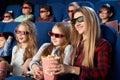 Mother and daughter in 3d glasses eating popcorn in cinema