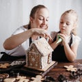 Mother and daughter decorating gingerbread house Royalty Free Stock Photo