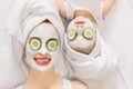 Mother and daughter doing funny spa procedures after bath. They are in white bath towels with white facial mud mask on Royalty Free Stock Photo