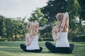 Mother and daughter doing yoga exercises on grass in the park at Royalty Free Stock Photo