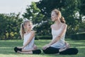 Mother and daughter doing yoga exercises on grass in the park at Royalty Free Stock Photo