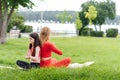 Mother and daughter doing yoga exercises on grass in the park at the day time. People having fun outdoors. Concept of friendly Royalty Free Stock Photo