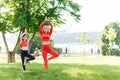 Mother and daughter doing yoga exercises on grass in the park at the day time. People having fun outdoors. Concept of friendly Royalty Free Stock Photo