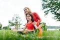 Mother and daughter doing yoga exercises on grass in the park at the day time. People having fun outdoors. Concept of friendly Royalty Free Stock Photo