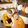 Mother and daughter drawing smiley face on a large Halloween pumpkin. Family decorating pumpkin.