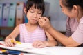 Mother and daughter drawing together with crayons. Adult woman helps girl study or draw together at home in living room. Happy