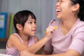 Mother and daughter drawing together with crayons. Adult woman helps girl study or draw together at home in living room. Happy