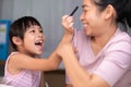 Mother and daughter drawing together with crayons. Adult woman helps girl study or draw together at home in living room. Happy