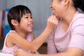 Mother and daughter drawing together with crayons. Adult woman helps girl study or draw together at home in living room. Happy