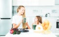 Mother and daughter drinking green smoothie in a white kitchen. Family mother and child daughter blended green and Royalty Free Stock Photo