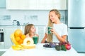 Mother and daughter drinking green smoothie in a white kitchen. Family mother and child daughter blended green and Royalty Free Stock Photo