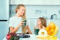 Mother and daughter drinking green smoothie in a white kitchen. Family mother and child daughter blended green and Royalty Free Stock Photo