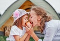 Mother and daughter eating apple near a tent in meadow or park. Happy family on picnic at camping Royalty Free Stock Photo