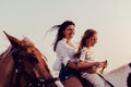 Mother and daughter enjoy riding horses together by the sea. Selective focus Royalty Free Stock Photo