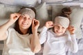 Mother and daughter enjoyed lazy morning together in cozy bedroom, wake up slowly, taking off blindfolds looking at camera smiling