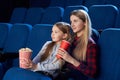 Mother and daughter enjoying movie in movie theatre.