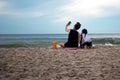 Mother and daughter enjoying vacation taking picture on cell phone by the beach