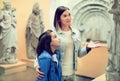 Mother and daughter exploring antique statues