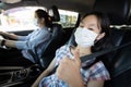Mother,daughter fastening seat belt in car,woman driving safety on the road,child girl thumbs up wearing a protective mask before