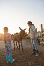 Mother and daughter feeding donkey in paddock Royalty Free Stock Photo