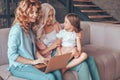 Mother, daughter and grandmother sitting on the couch and using laptop together Royalty Free Stock Photo