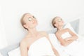 Mother and daughter had a day of spa. They are in white bath towels with slices of cucumber on their eyes Royalty Free Stock Photo