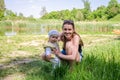 Mother and daughter happy family in a meadow on the shore of the lake in the grass