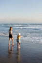 Mother with daughter have fun at beach with black sand in Bali, running at waves, enjoy life and traveling.