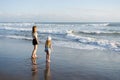 Mother with daughter have fun at beach with black sand in Bali, running at waves, enjoy life and traveling.