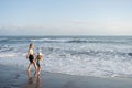 Mother with daughter have fun at beach with black sand in Bali, running at waves, enjoy life and traveling.