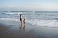 Mother with daughter have fun at beach with black sand in Bali, running at waves, enjoy life and traveling. Royalty Free Stock Photo