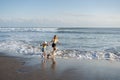 Mother with daughter have fun at beach with black sand in Bali, running at waves, enjoy life and traveling.